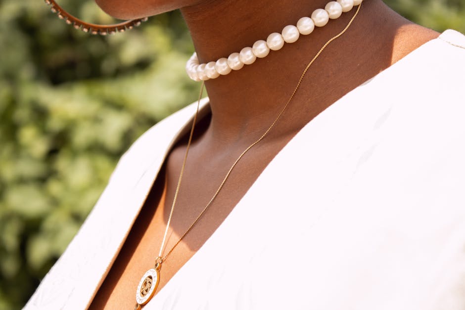 Crop anonymous female wearing stylish accessories standing on street against green trees in sunny day