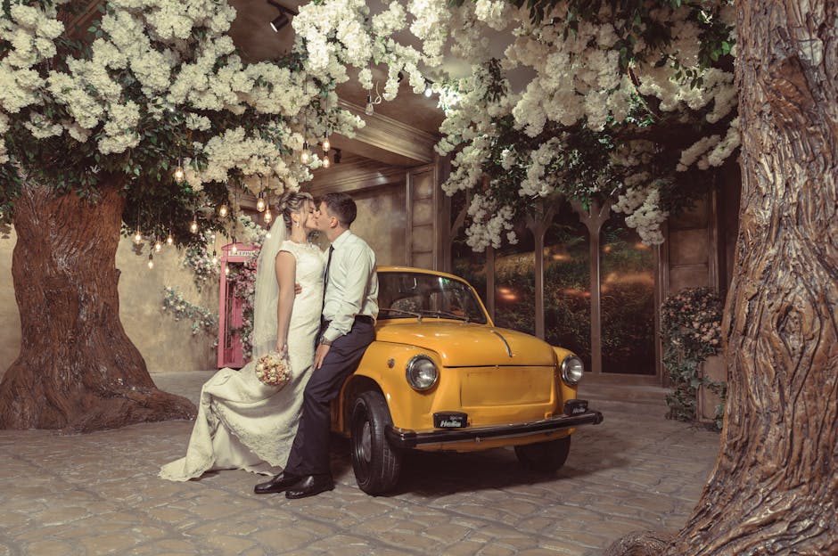 Romantic newlyweds kissing near retro car