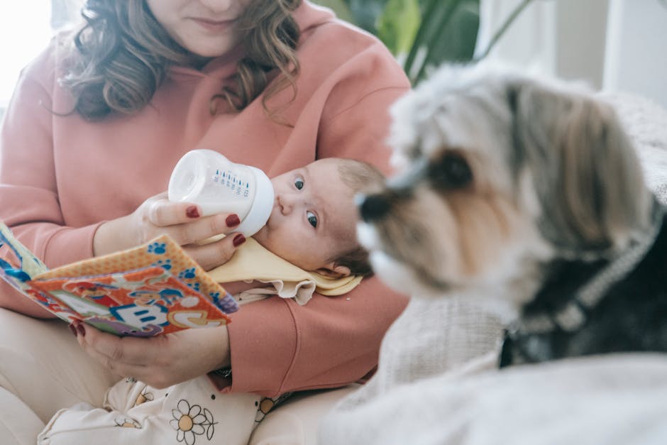 Faceless mother feeding newborn baby near dog