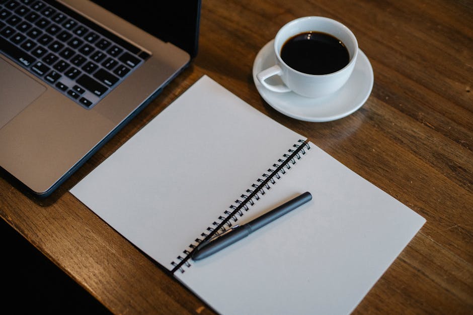 Laptop and notepad near cup of coffee