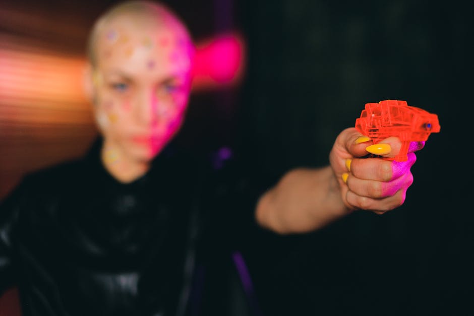 Eccentric bald woman pointing toy gun in dark studio