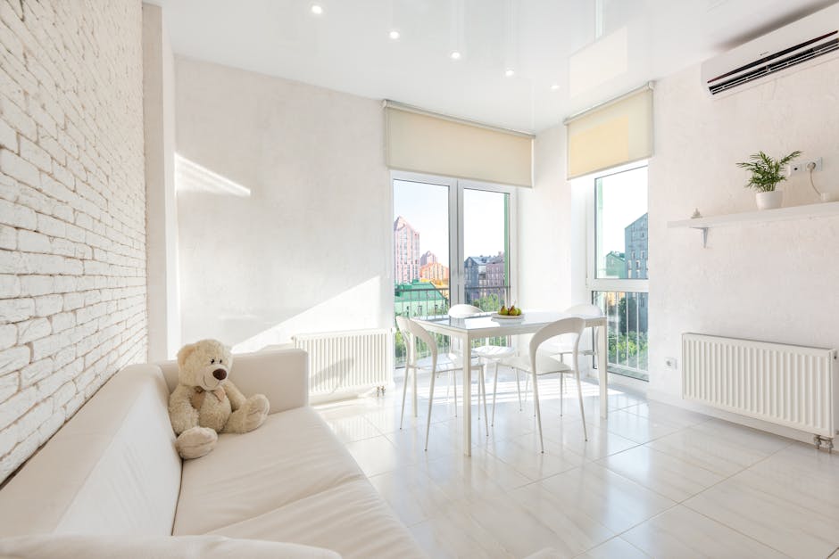 Interior of white kitchen furnished with sofa and chairs and table placed near big windows with blinds