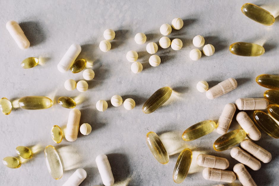 Top view of scattered set of pills and dietary supplements to prevent lack of vitamins on table in light studio