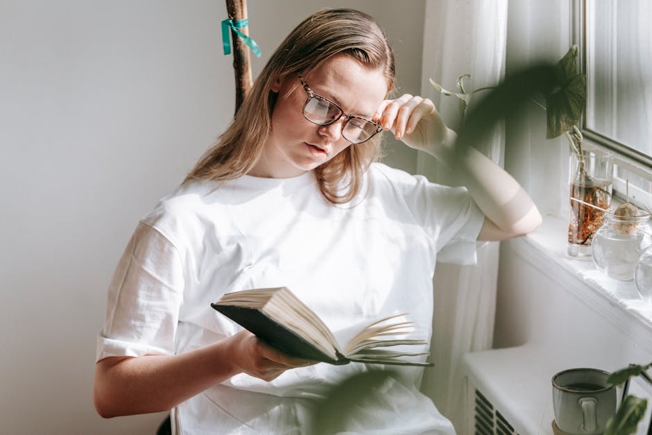 Attentive woman in eyewear reading notebook at home