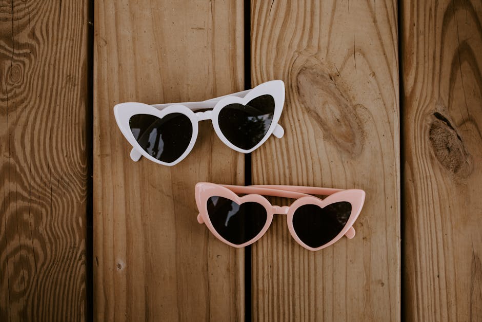 Stylish heart shaped sunglasses on wooden surface