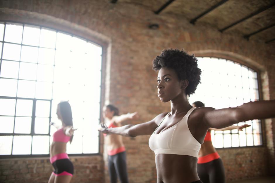 Confident fit ethnic woman training with other sportswomen in modern fitness studio