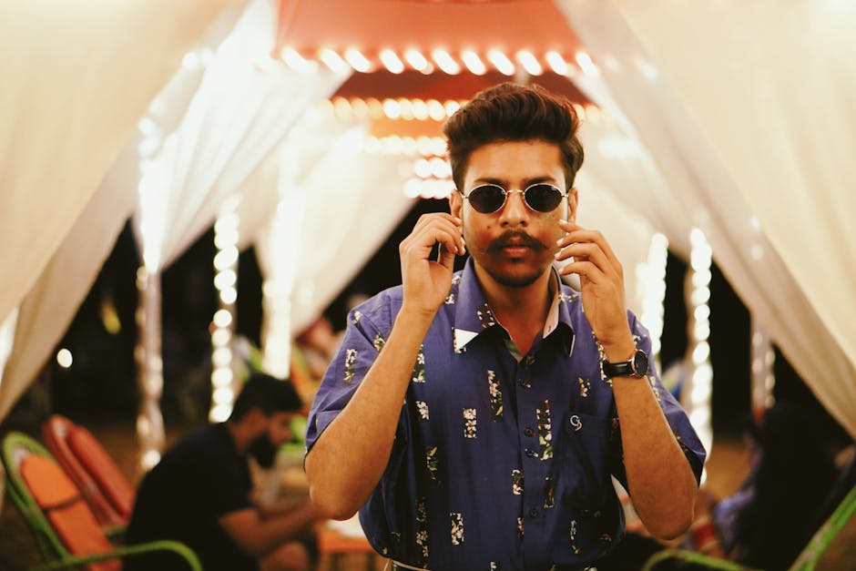 Serious ethnic guy in illuminated outdoor cafe in evening