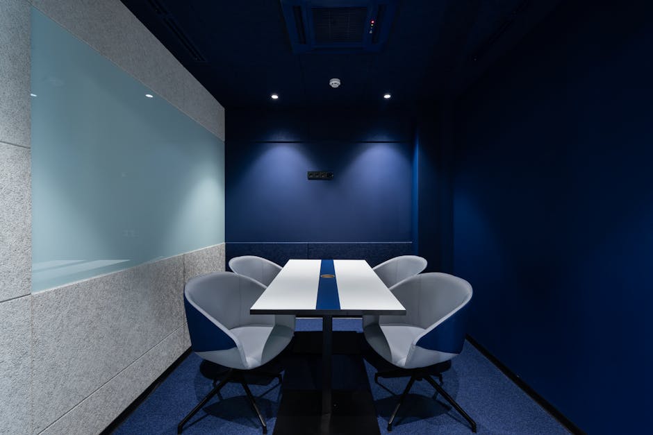 Comfortable chairs placed on carpet at long white desk in modern conference room with blue walls in contemporary business center