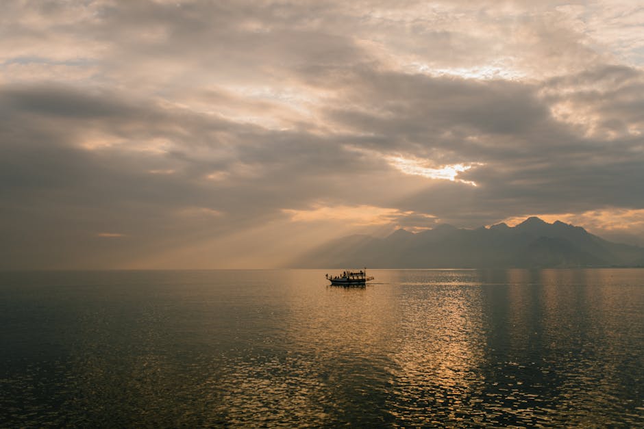 Picturesque scenery of boat floating on rippling water of sea against amazing cloudy sunset sky