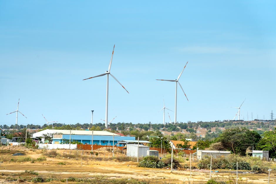 Scenic view of wind turbines against houses under cloudy blue sky in countryside in daytime