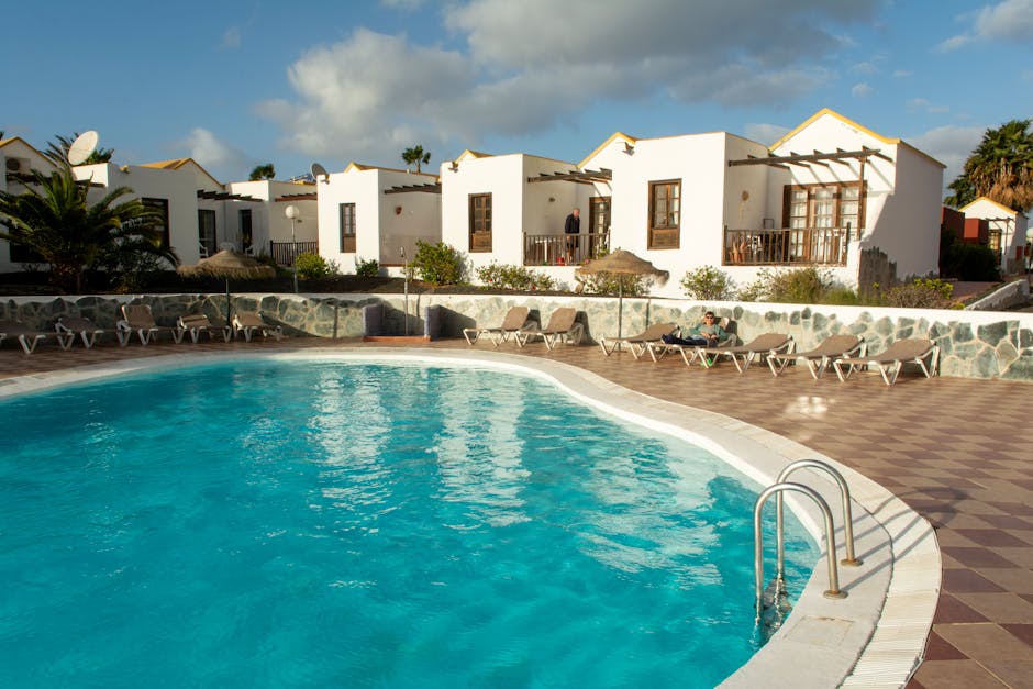 A pool with lounge chairs and umbrellas in front of it