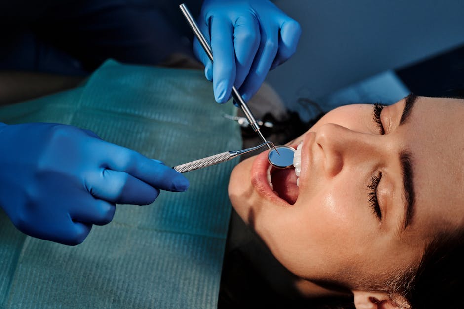 A Person Wearing Blue Latex Gloves Holding a Mirror in a Woman’s Mouth