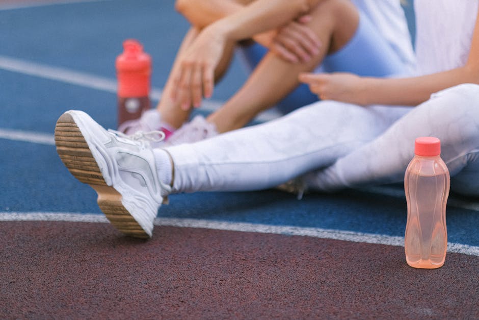 Anonymous female friends sitting on sports ground after training