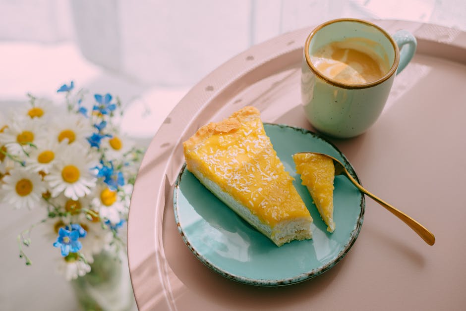 From above of delicious latte coffee in ceramic mug and slice of cheese cake on plate served on tray and bunch of field flowers on table