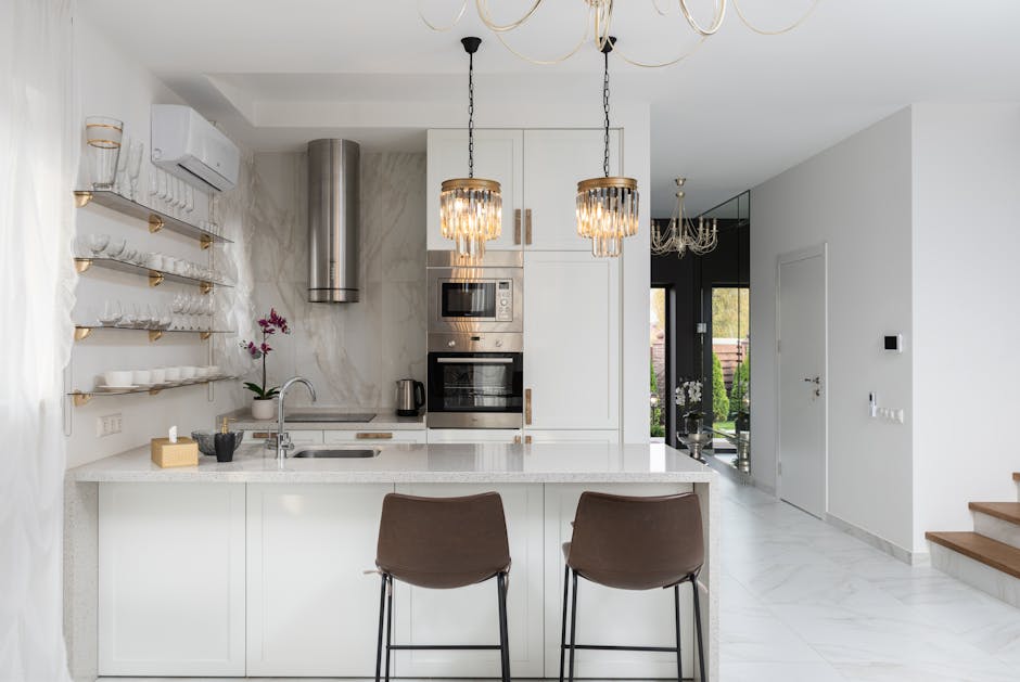 Interior of contemporary kitchen with modern appliances and chairs at white counter near  wall with shelves in spacious apartment near stairs