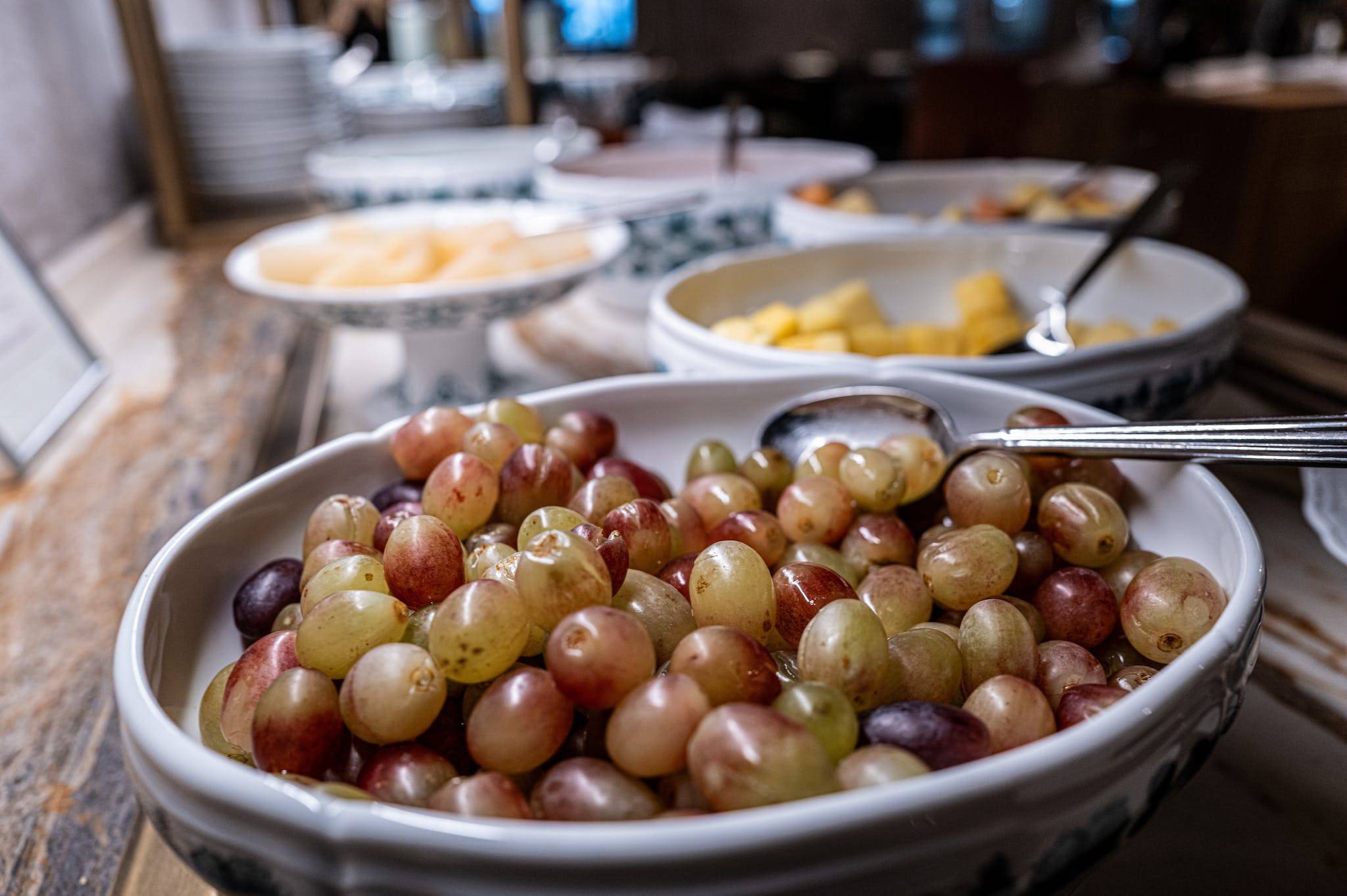 A buffet with bowls of grapes and other fruit