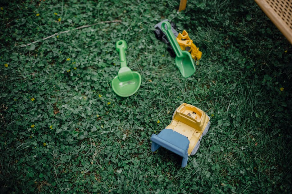 High angle of green grass and colourful plastic kids toys on garden meadow