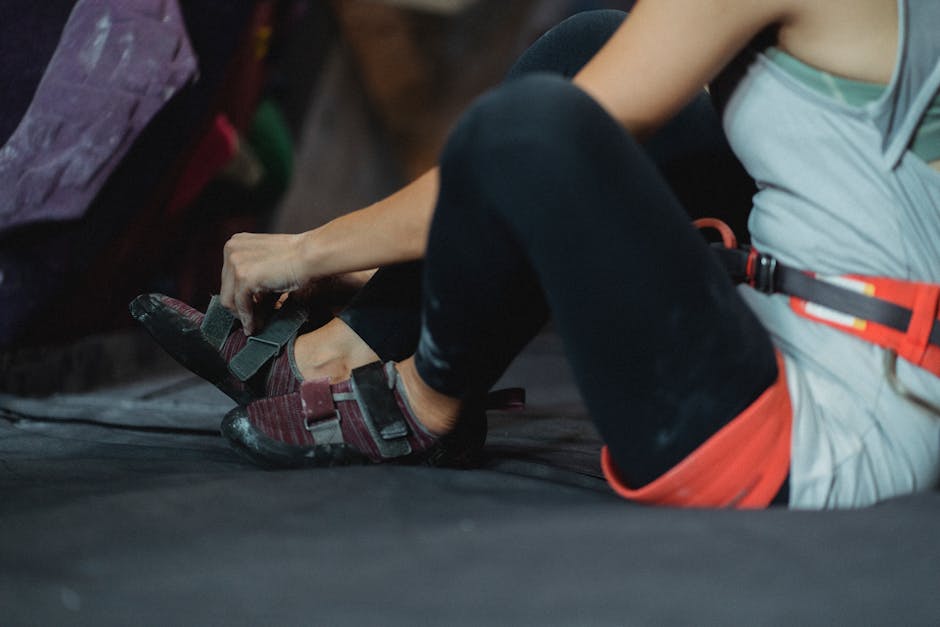 Sportswoman putting on sneakers for climbing