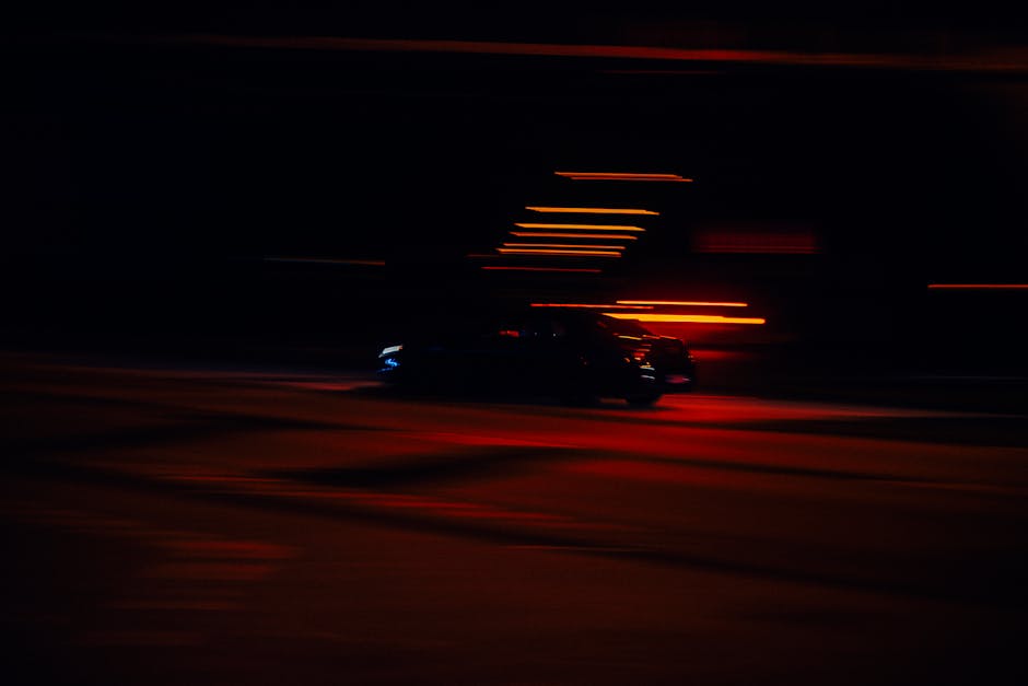 A car is driving down the road at night