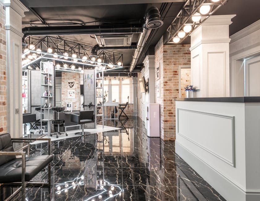 Reception counter placed in spacious stylish beauty salon with black chairs and decorated bricks walls with paintings under bright illumination