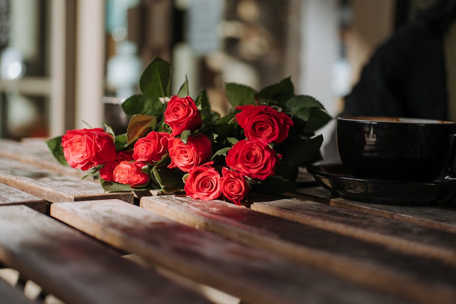 Bright blooming roses near cup of coffee in cafe