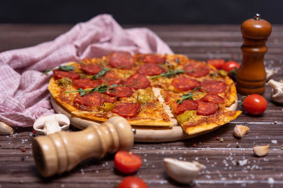 Pizza with Salami and Pepper and Salt Grinders on a Table