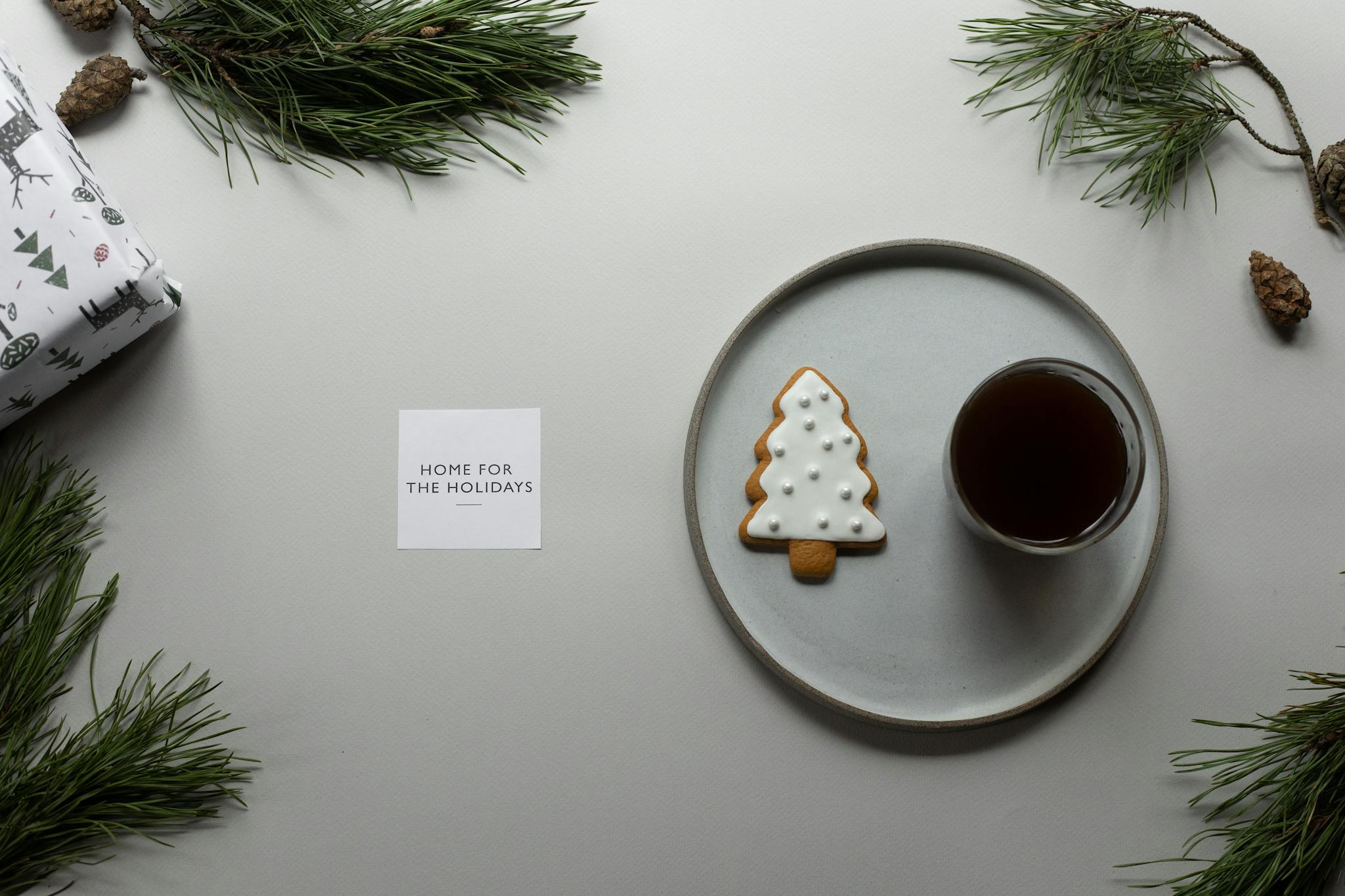 Composition of coffee and cookie on table with greeting card and coniferous branches