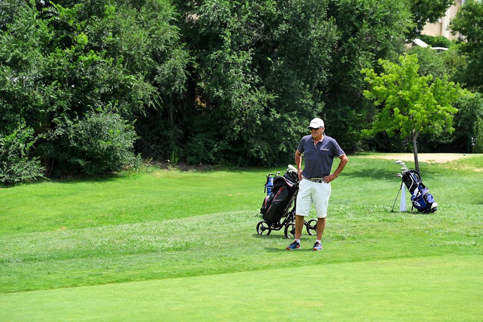 A man standing on a golf course with a golf bag