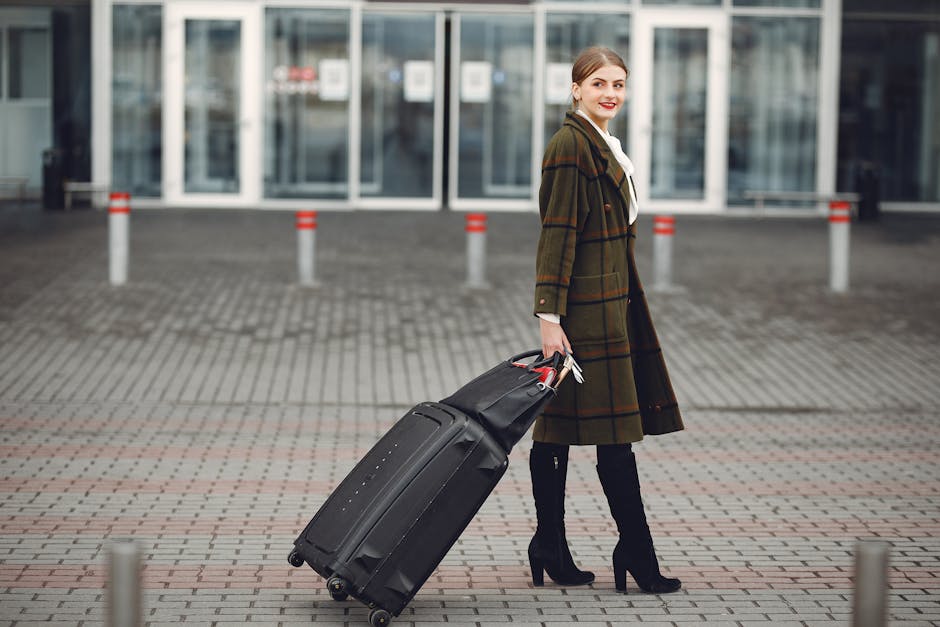 Full length of smiling female manager in stylish coat walking with suitcase and bag while traveling on business trip smiling away