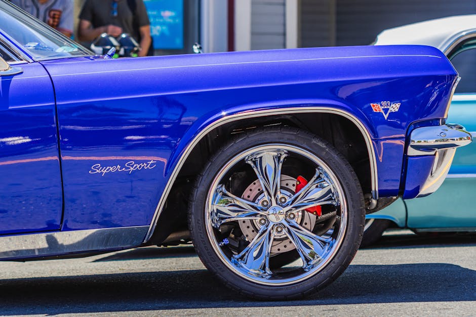 A blue car with a chrome wheel and a man standing next to it