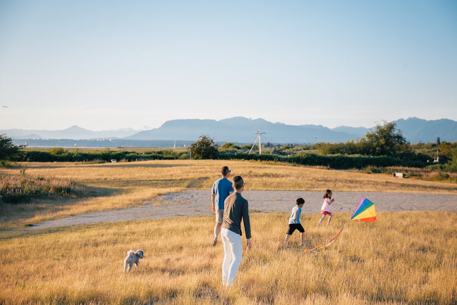 Happy Family Having Fun Playing with Kite in the Grass Field