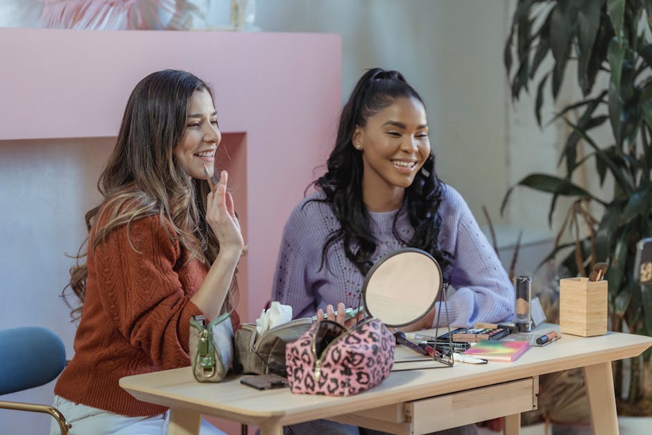 Diverse cheerful women smiling and looking away at table with different cosmetics and round shaped mirror