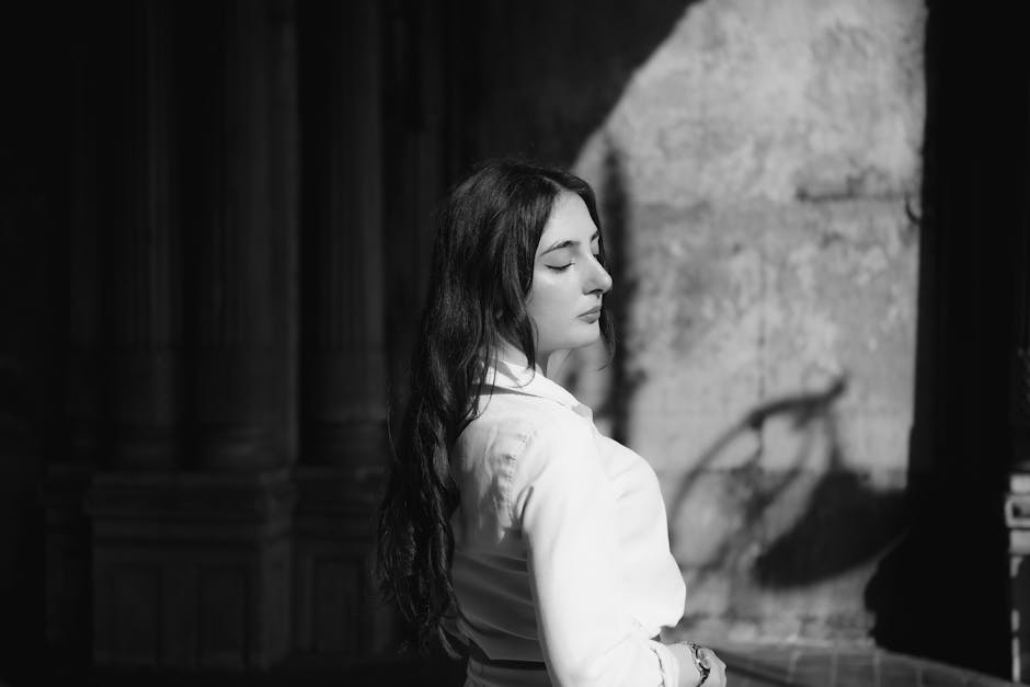 A woman in white shirt and jeans standing in the sun