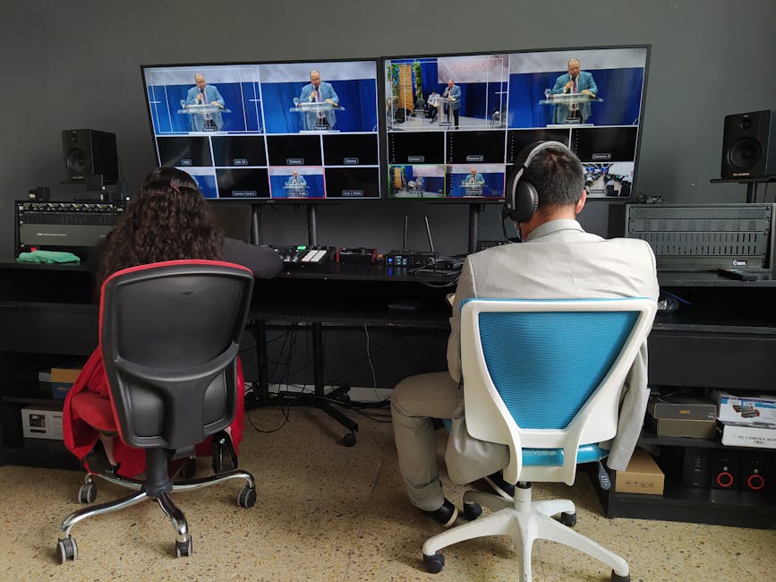 Back view of broadcast editors working at panel with equipment and big monitors