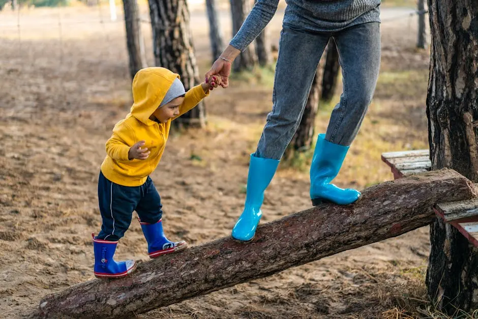 A woman helps her toddler walk on a log in a park, showcasing child support and family bonding.