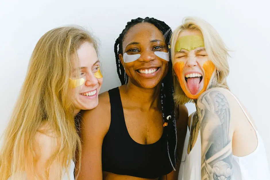 Three diverse women having fun with colorful skincare masks, embodying friendship and joy.