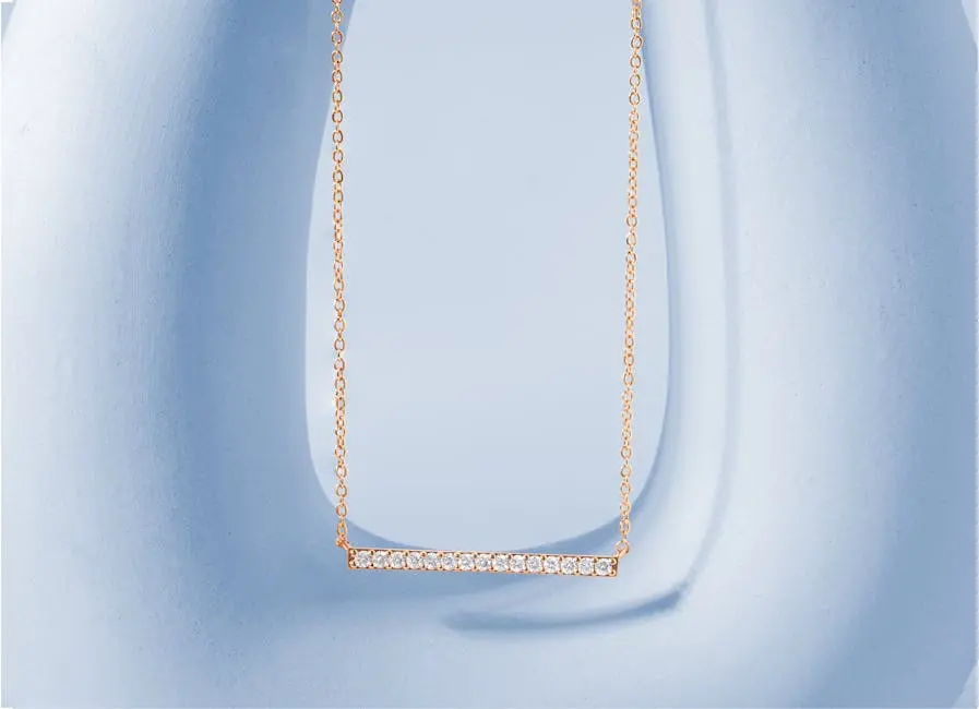 Close-up of a luxurious gold necklace with a diamond pendant on a light blue background, perfect for jewelry advertisements.