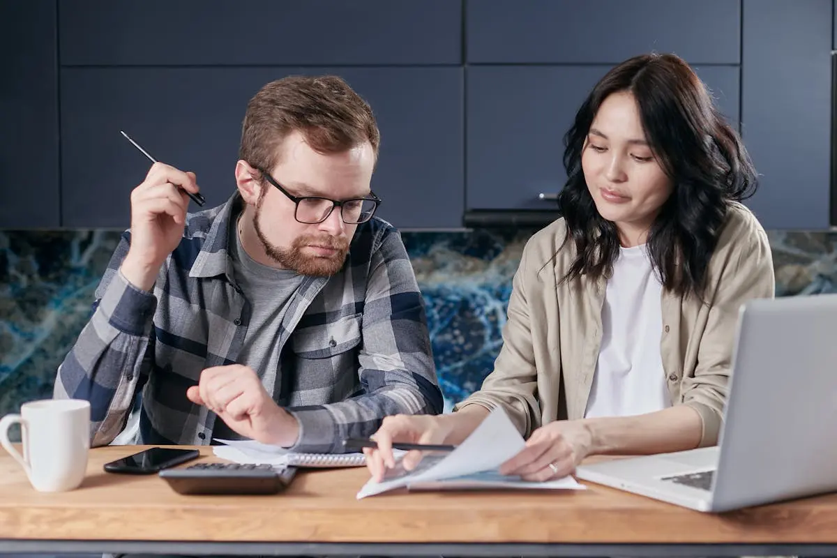 A Couple Looking at a Paper on a Desk with a Calculator