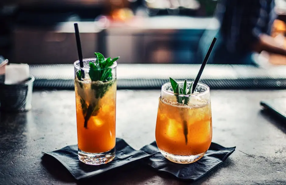 Two chilled cocktails with mint and ice on a bar counter, garnished with fresh mint leaves.