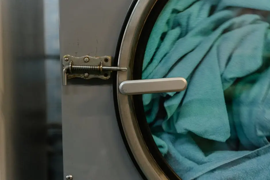 Detailed view of a commercial washing machine with blue fabric inside during a wash cycle.