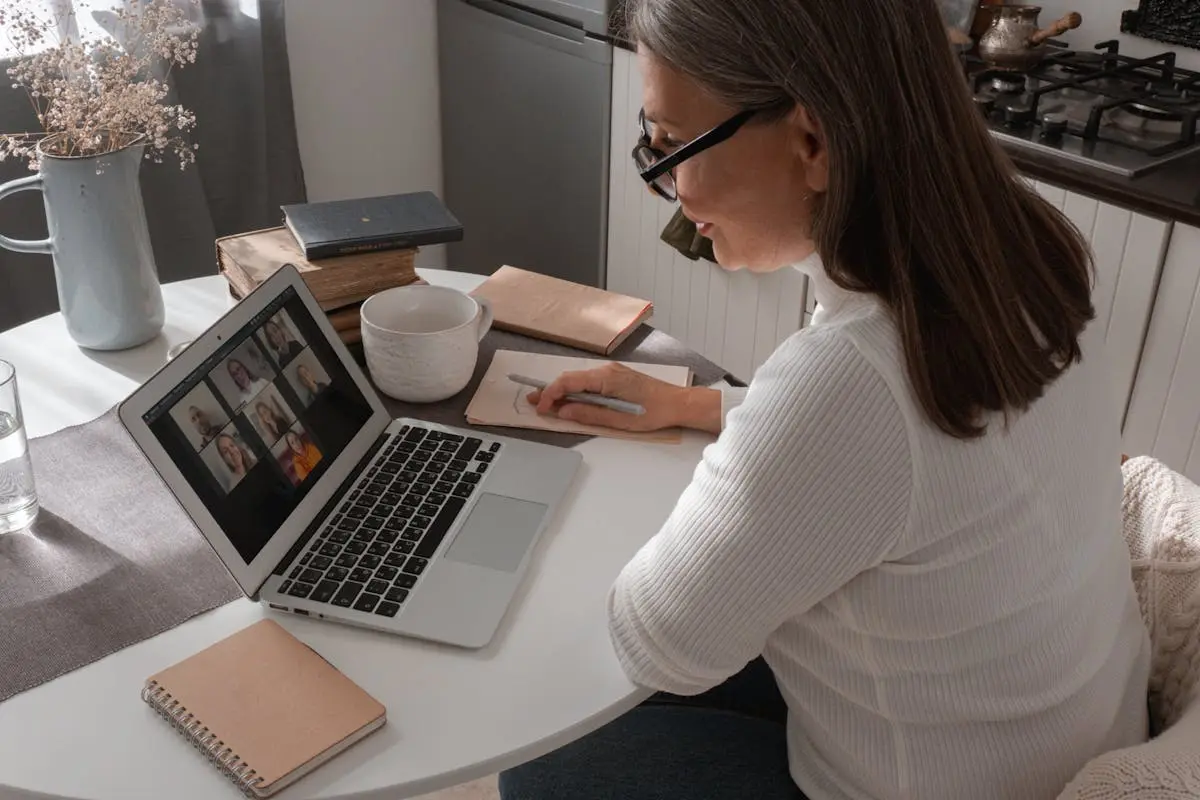 Woman Sitting at a Table and Using a Laptop 