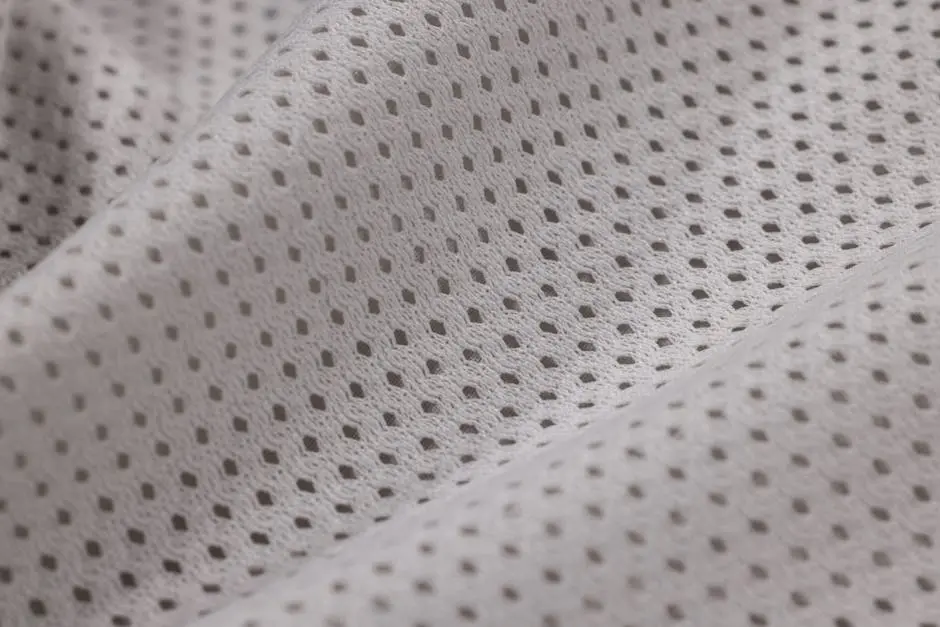 Macro shot of white mesh textile displaying intricate weave pattern, ideal for sportswear.