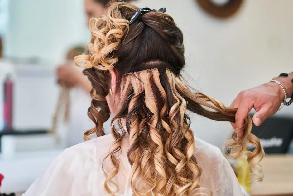 Close-up of hairstylist perfecting curls on a woman’s hair in a salon setting.