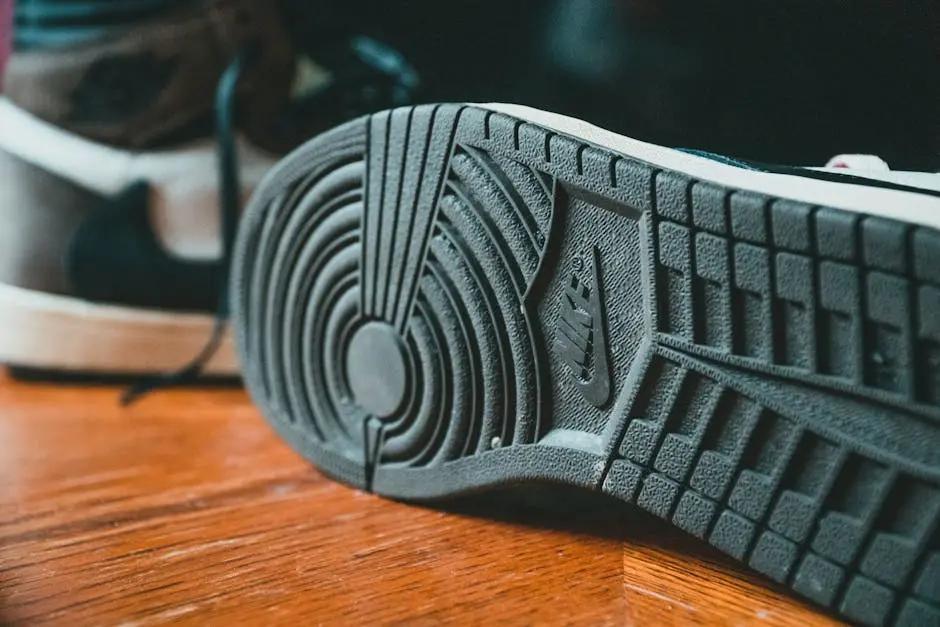 Closeup of black rubberized sole of modern stylish sneakers placed on wooden floor