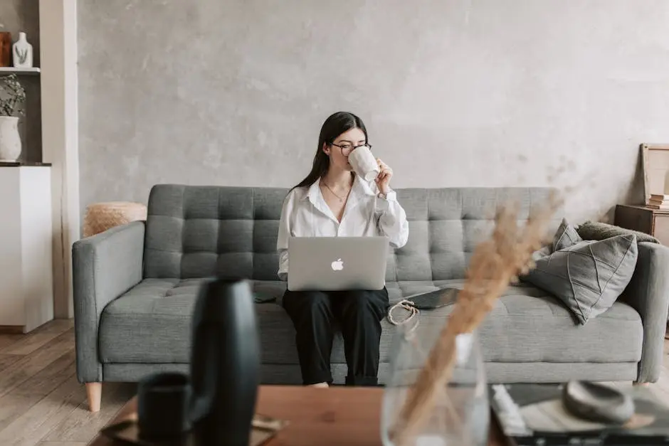 Mujer tomando café mientras trabaja con un portátil en un acogedor entorno doméstico, destacando el estilo de vida del trabajo a distancia.