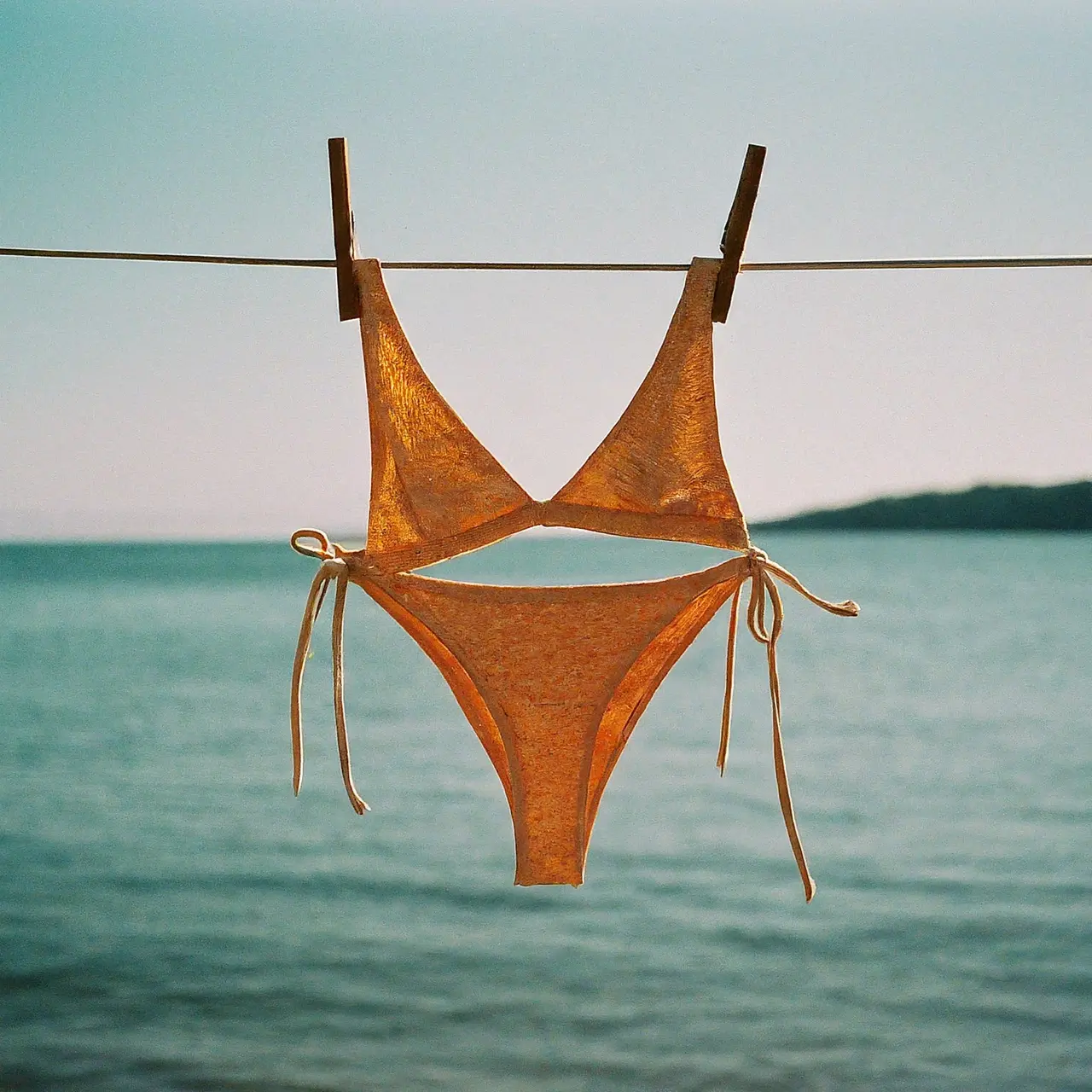 Colorful eco-friendly bikinis hanging on a clothesline by the sea. 35mm stock photo