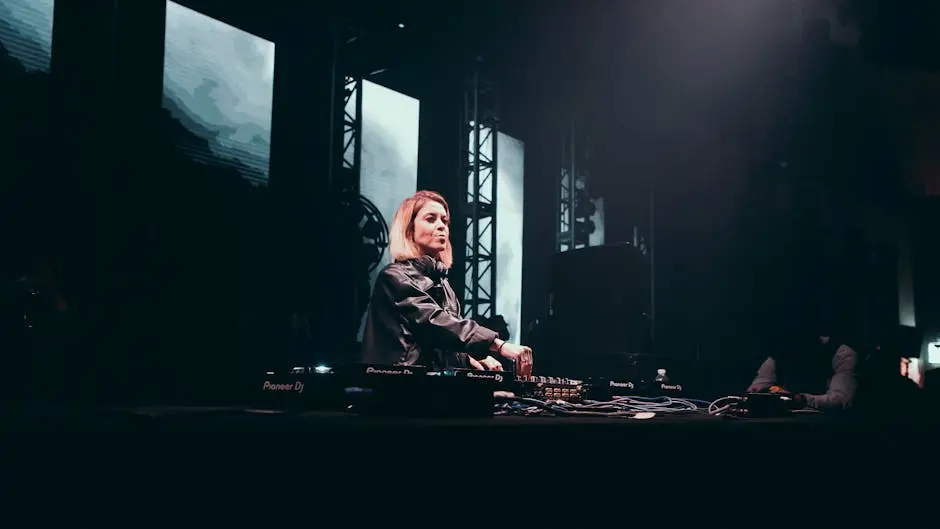 A female DJ playing an energetic live set onstage with dynamic lighting and visuals.