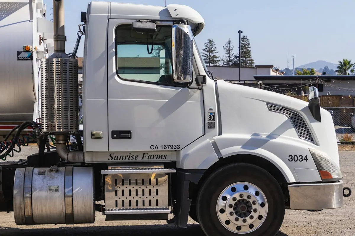 Side view of a white semi-trailer truck parked outdoors in an industrial area.