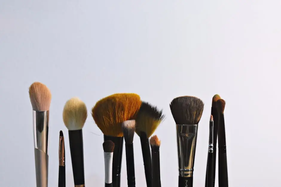 A variety of makeup brushes arranged vertically on a plain backdrop, perfect for beauty and cosmetic themes.