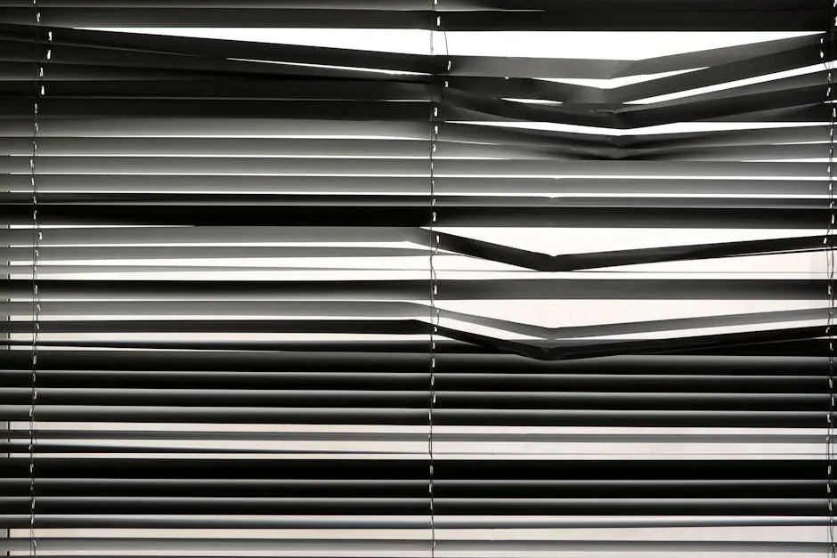 Horizontal venetian blinds creating a shadow pattern indoors with strong sunlight.